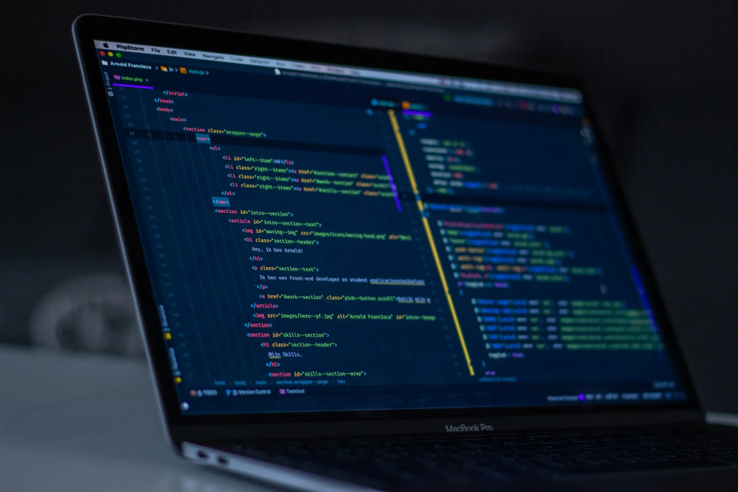 Laptop on a desk showing lines of code in a dark editor