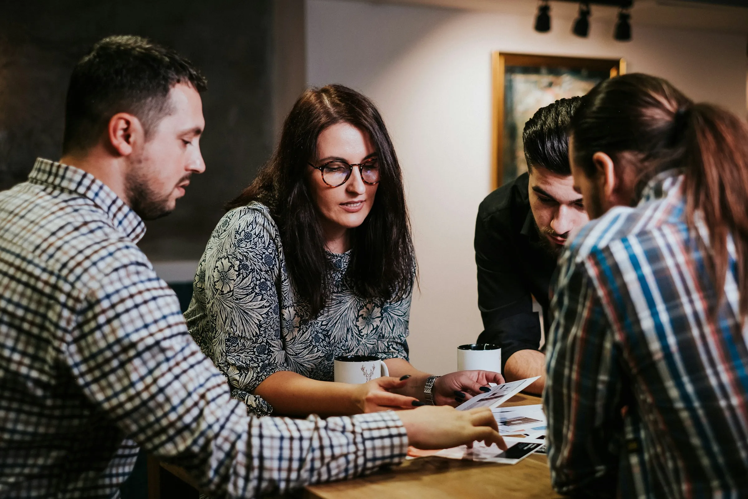 Four people around a table reviewing printed design options together