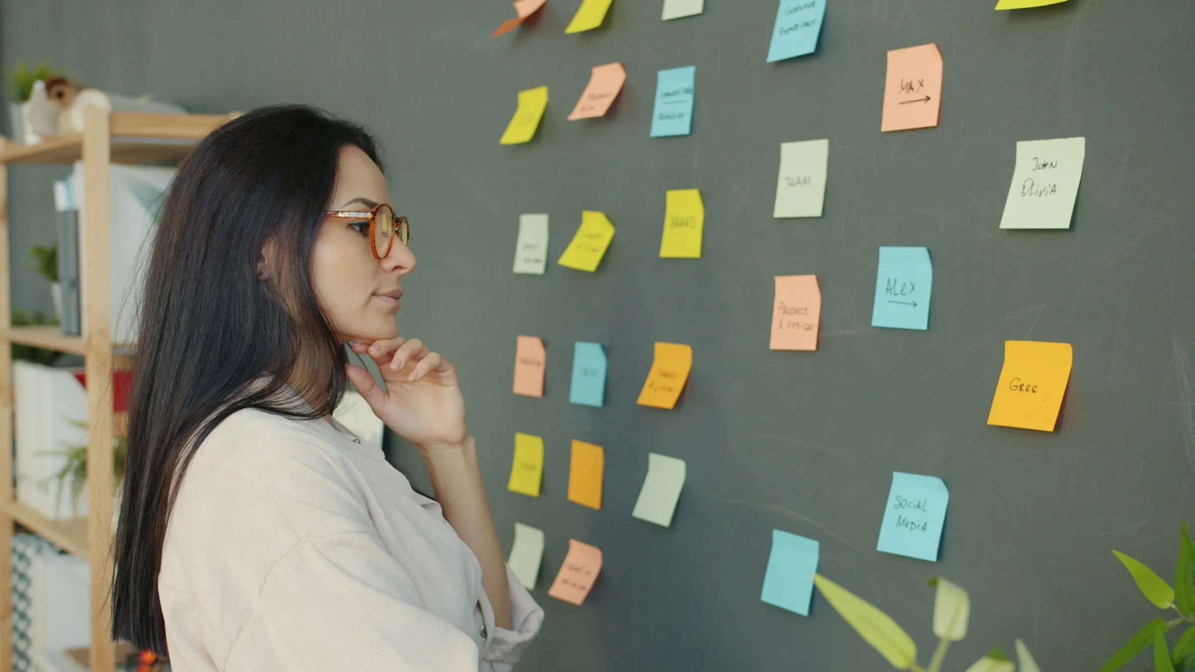 Woman studying a wall of colorful sticky notes while sorting research findings