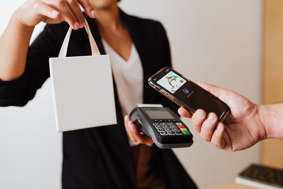 Person paying cashless with a phone, illustrating fintech UX for irreversible money-movement actions